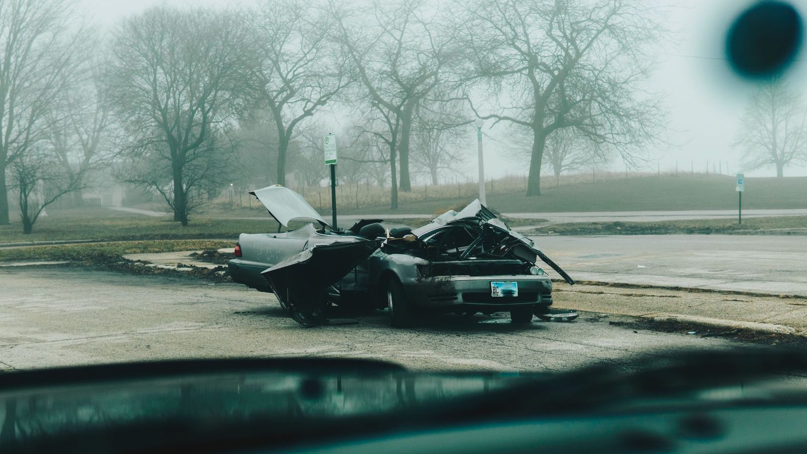 A severely damaged car on a deserted, foggy street in Chicago on a misty morning.