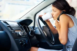 A person driving distracted, drinking coffee while being on the phone.