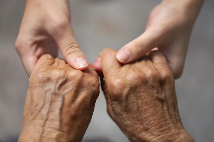 A younger pair of hands holding an older pair of hands.