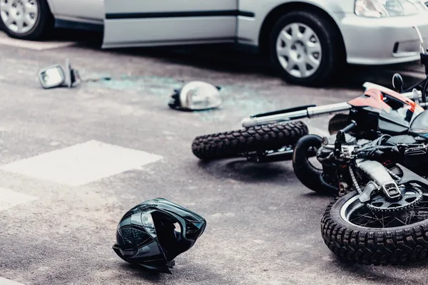 Helmet, mirror and a car lamp between car and motorcycle after terrible road accident