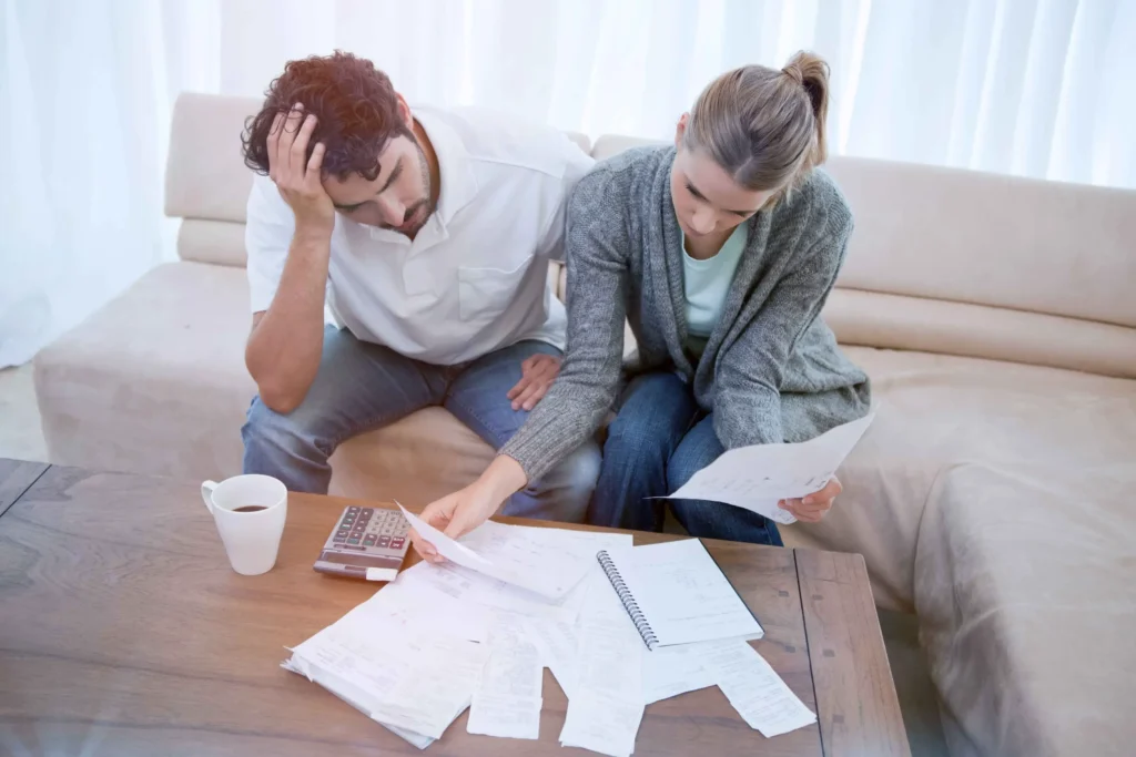 A couple sitting on a couch going over bills.