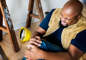 A person injured at work, holding their leg in pain.