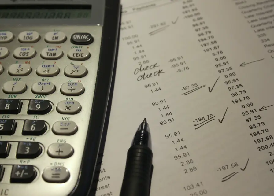 A calculator and a pen along a list of expenses.