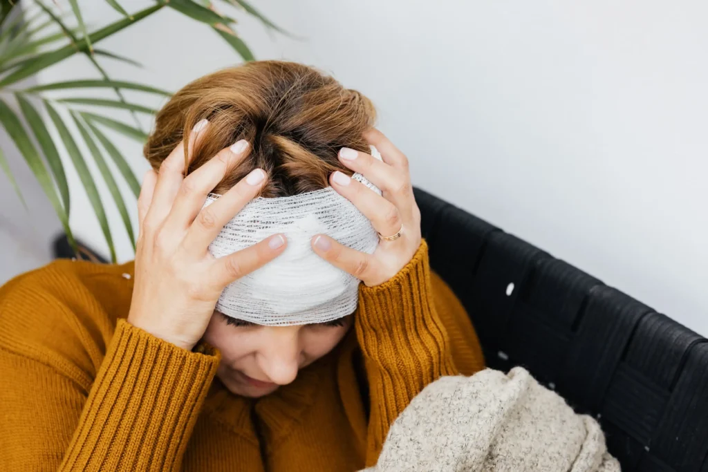 A woman with her wrapped head holding her head in pain.